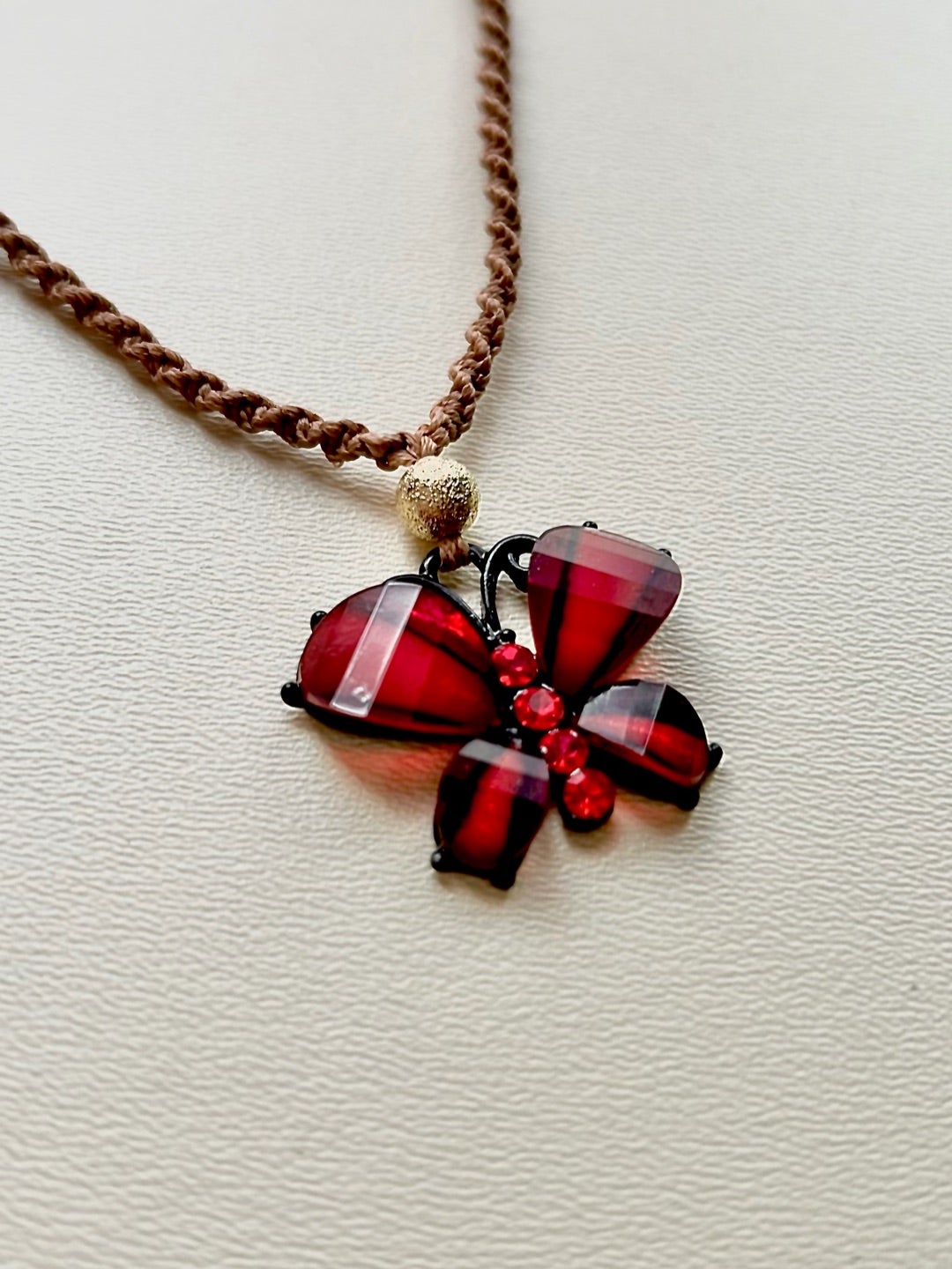 透明で深いレッドの蝶をモチーフにマクラメネックレスを制作しました。薄茶のマクラメコード使用。